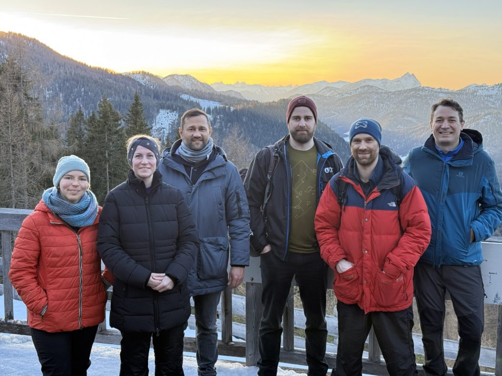 Mitarbeiterinnen und Mitarbeiter der Glood GmbH vor dem Hintergrund von schneebedeckten Berggipfeln
